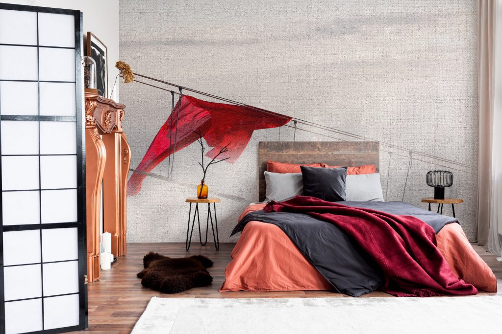 Copie el espacio en la pared blanca vacía del interior de la habitación rústica con cama king size con ropa de cama naranja y manta burdeos